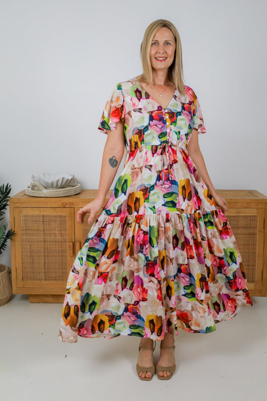 Woman wearing a colorful floral dress standing against a white background