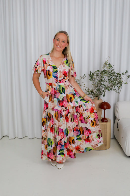 Woman in a colorful dress sitting on a white couch with a white curtain background
