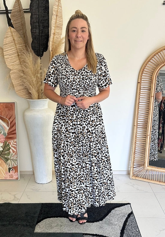 Woman wearing a black and white patterned dress standing in a room with decor elements.