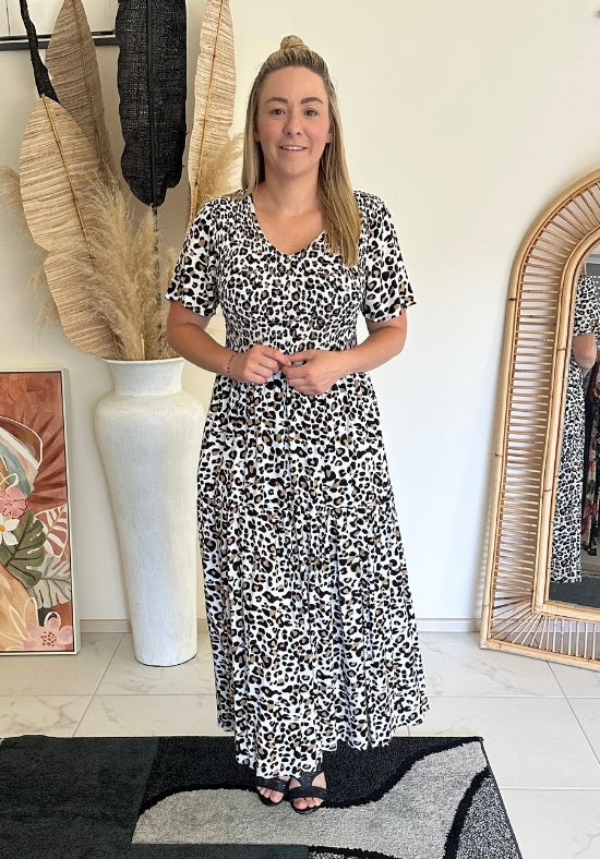 Woman wearing a black and white patterned dress standing in a room with decor elements.