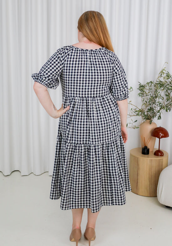 Woman wearing a black and white checkered dress in a minimalistic room.