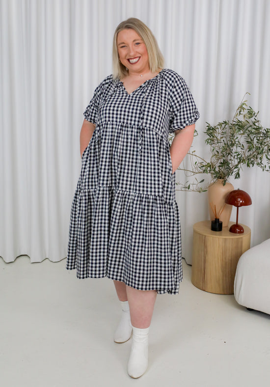 Woman wearing a black and white checkered dress in a minimalistic room.